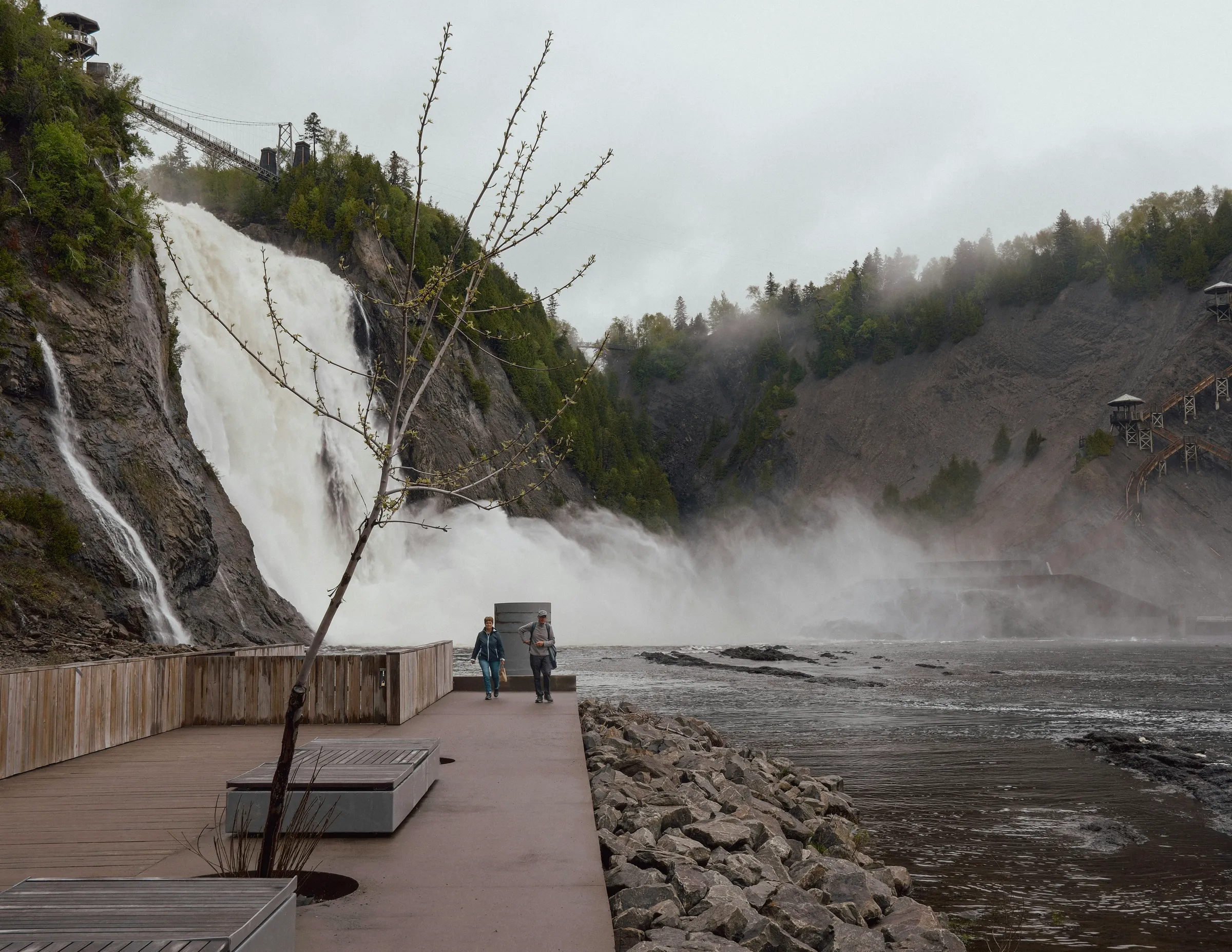 Powerful waterfall with misty spray next to a concrete walkway