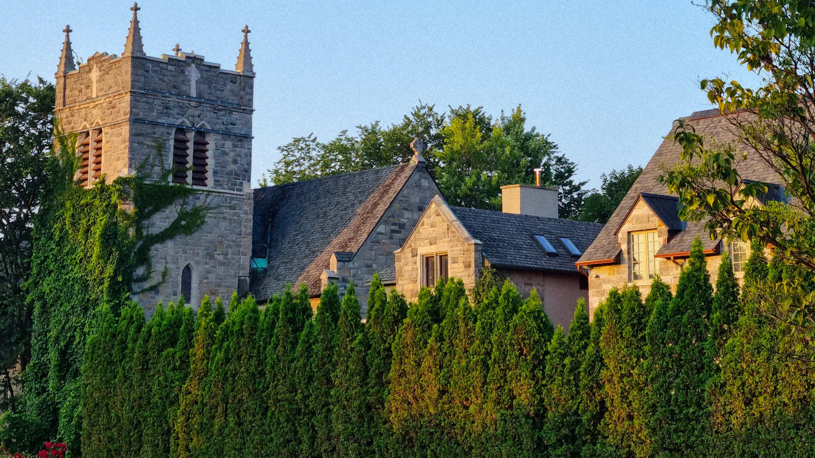 a large building with a clock tower next to a lush green field
