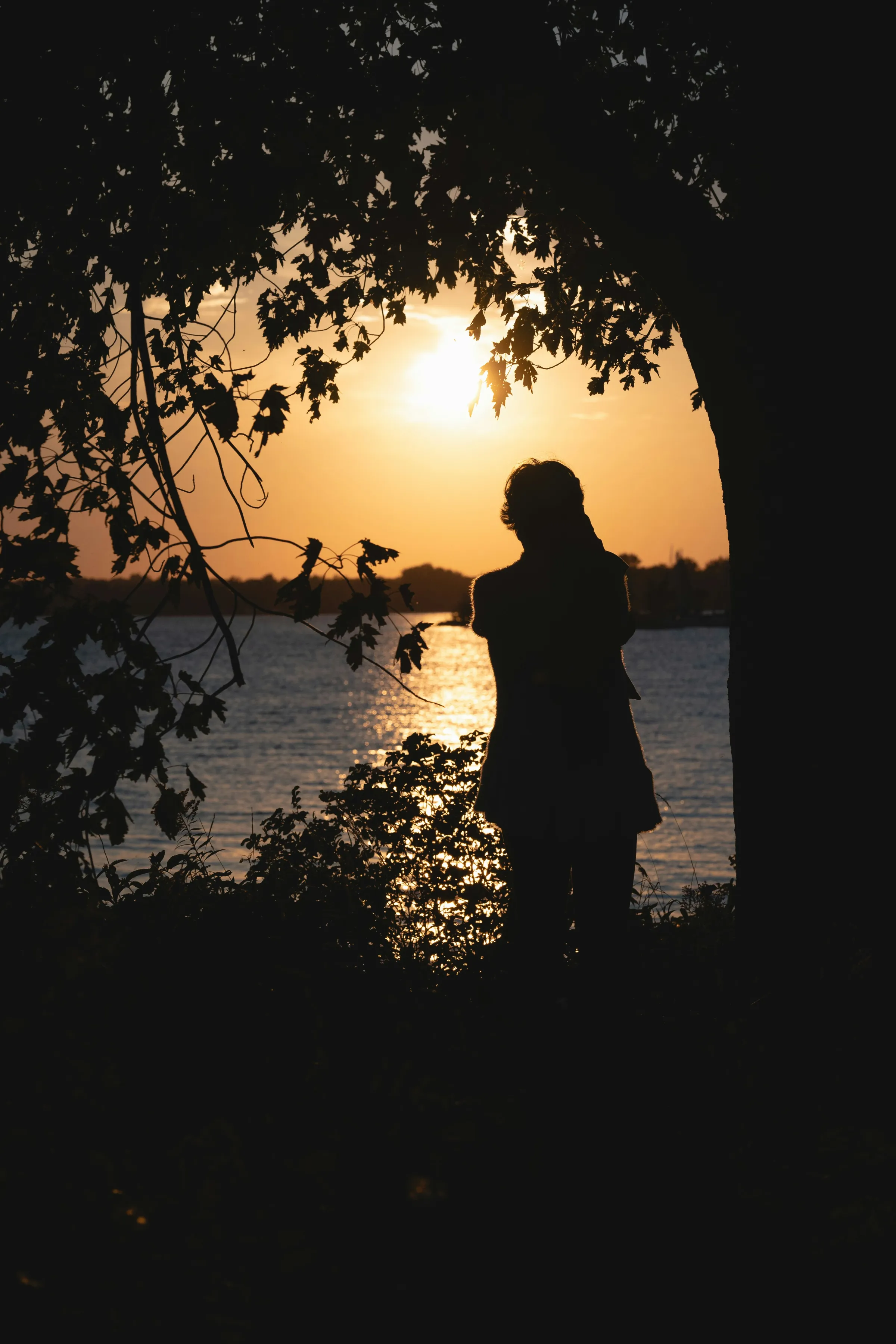 Silhouette d'une personne devant le lac au coucher du soleil, à Pointe-Claire