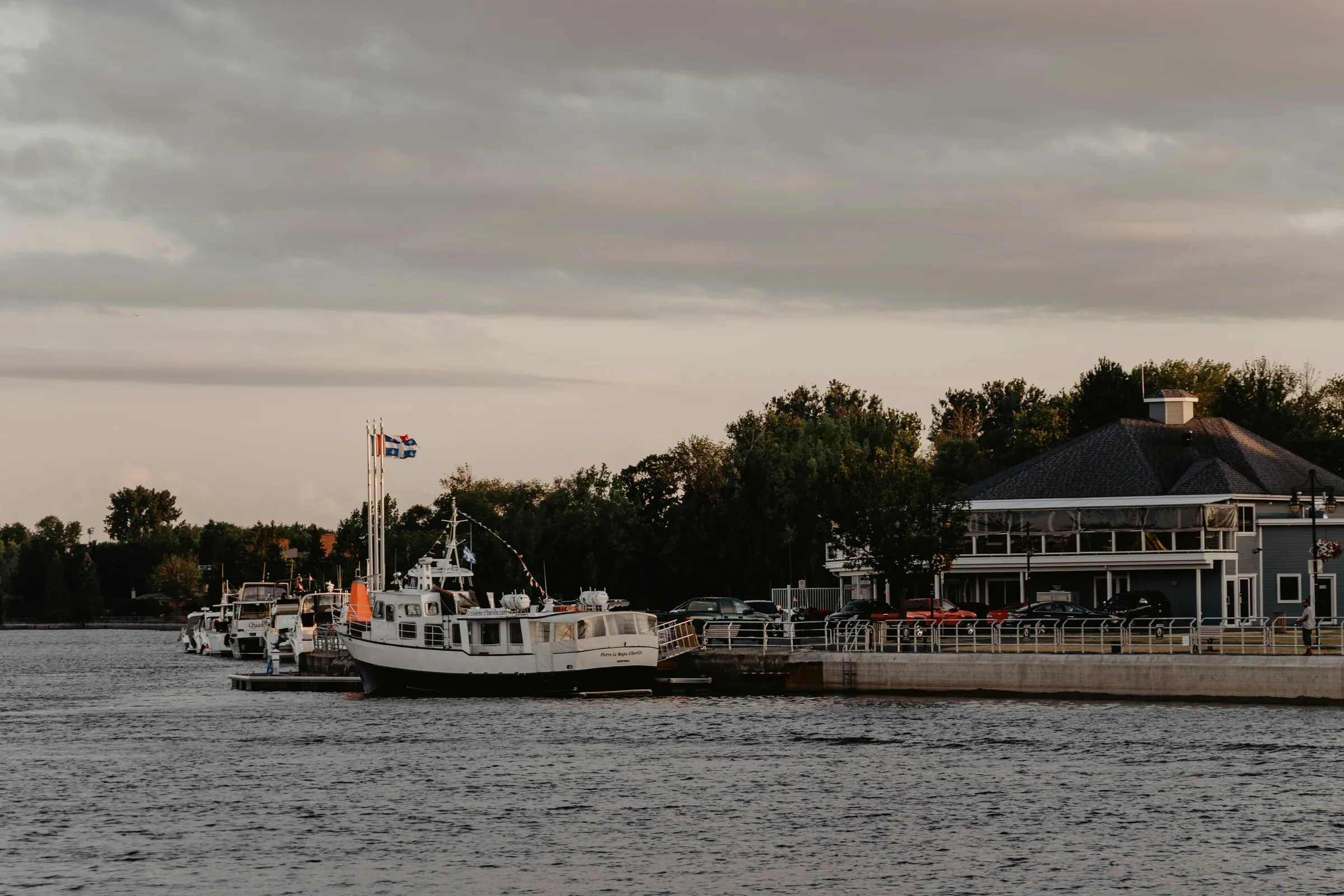 Several boats are docked at a pier on a cloudy day