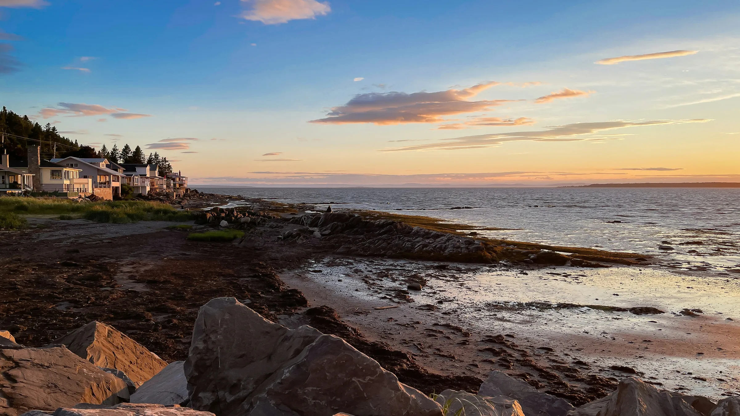 a rocky beach with houses and water
